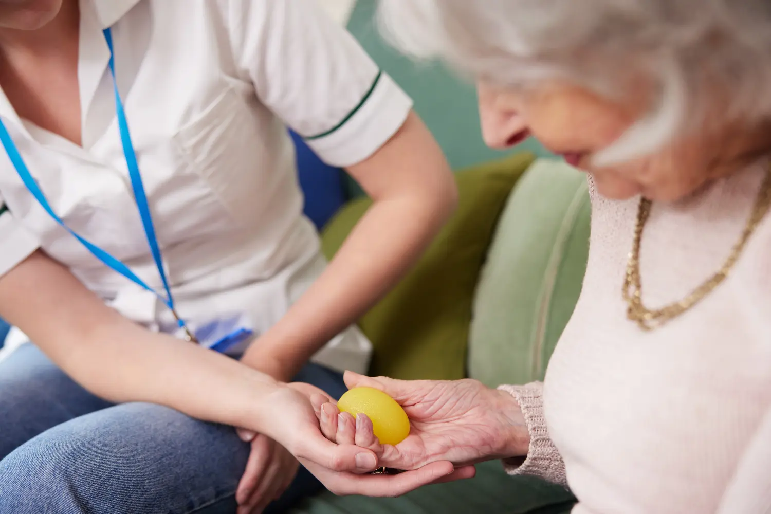 Physiotherapeutin bringt ältere Frau dazu, zu Hause einen Gummiball zu drücken