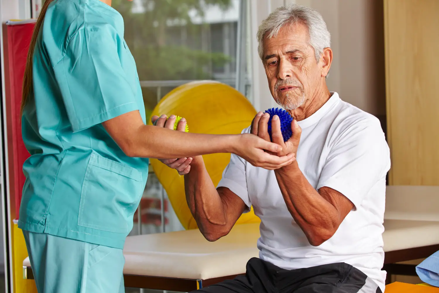 Senior mit Igelball bei Physiotherapie 